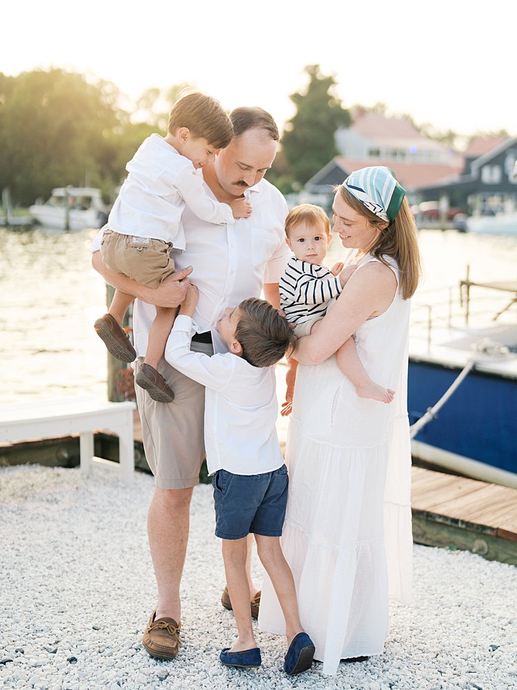 Mother, father, and their three sons stand along a dock during their St. Michael's family photos.