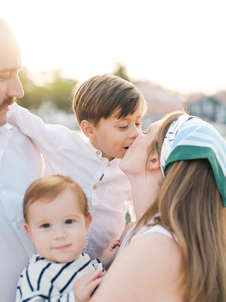 A son kisses his mother during their golden hour family photo session in St. Michael's, MD.