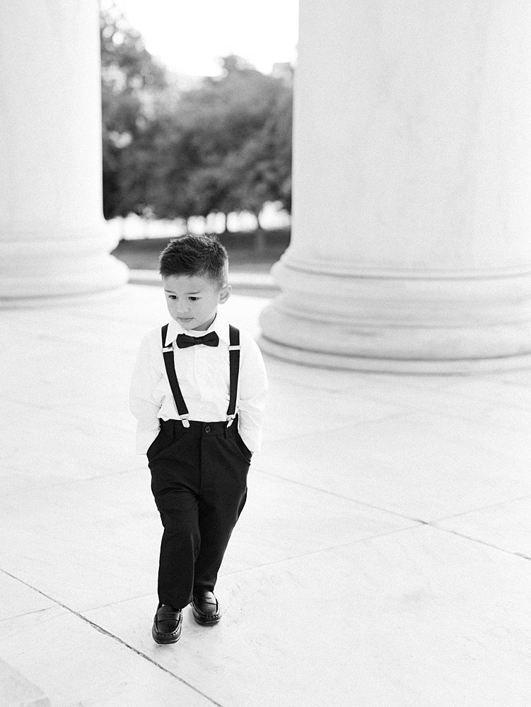 A Little Boy In A Tux Stands With His Hands In His Pockets.