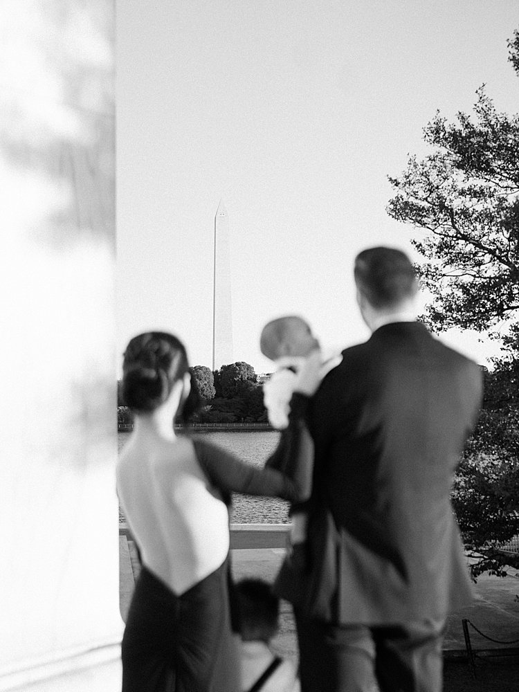 A Black And White Image Of A Family Looking Out At The Washington Monument From The Jefferson Memorial.
