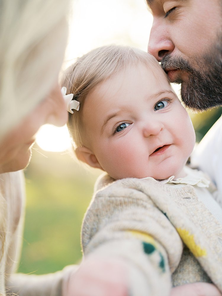 A Father Leans In To Kiss His Infant Daughter's Cheek During Their Jones Point Park Family Photos.