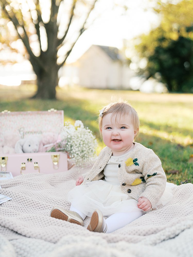 A One Year Old Girl Sits On A Blanket For Her One Year Photos At Jones Point Park.