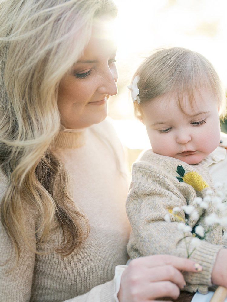 A Blonde Mother Holds Baby's Breath To Her Infant Daughter During Their Jones Point Park Family Photos.