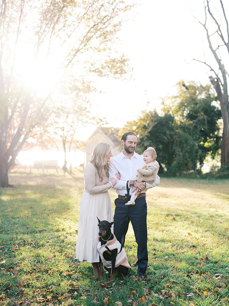 A Mother And Father Stand In Jones Point Park In Alexandria With Their Baby Girl And Dog.