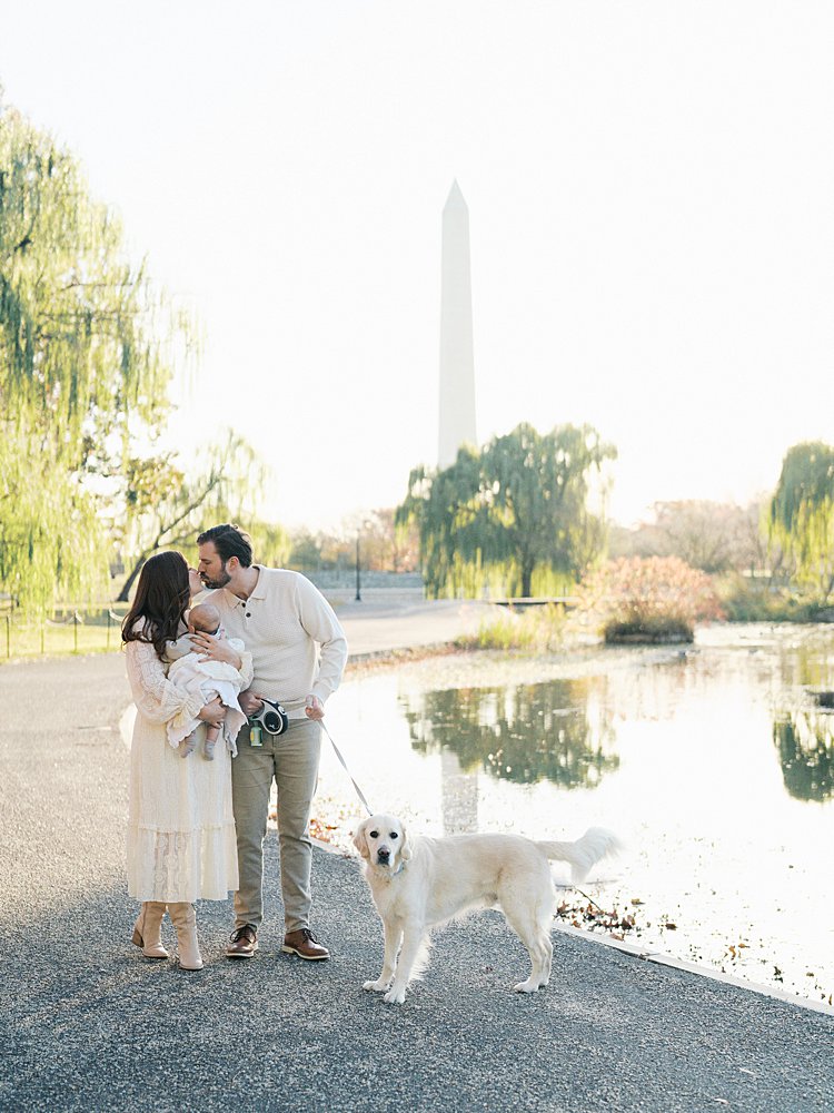 Mother And Father Lean In To Kiss While Having Their Dog On A Leash At Constitution Gardens In Washington, D.c.