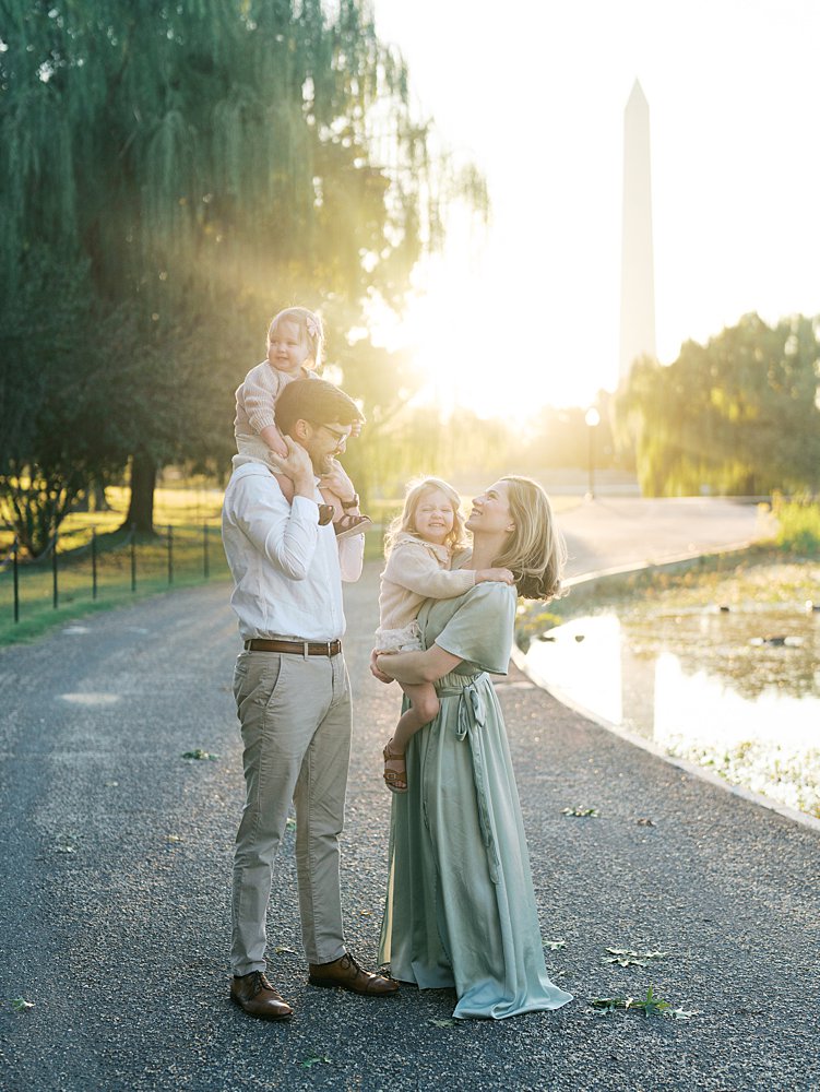 Family Of Four Smile And Laugh During Their Downtown Dc Family Photos At Constitution Gardens.