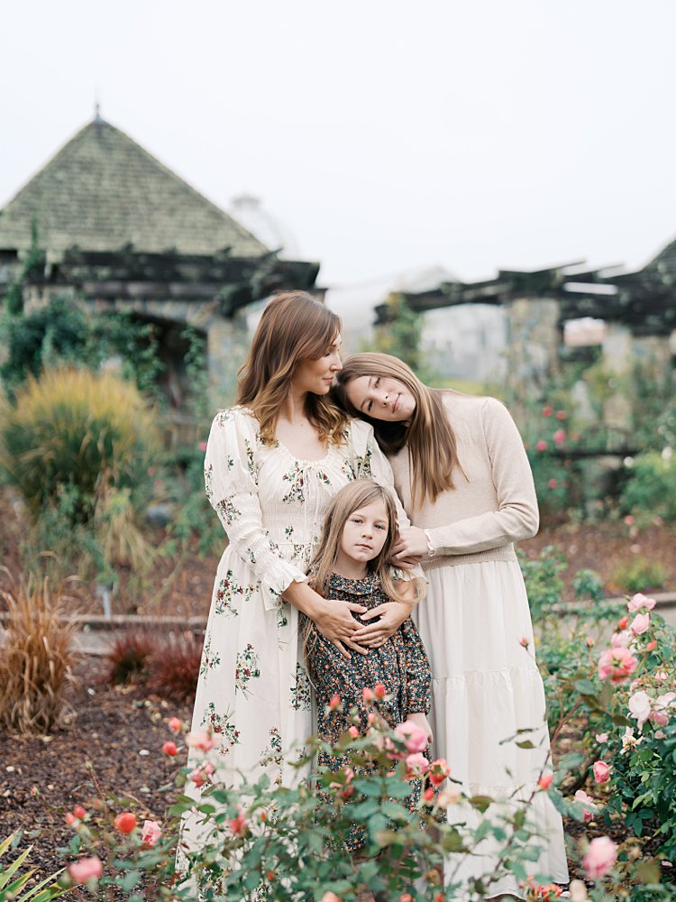 A Mother Has Her Two Daughters Leaning Against Her In The Lewis Ginter Botanical Garden.