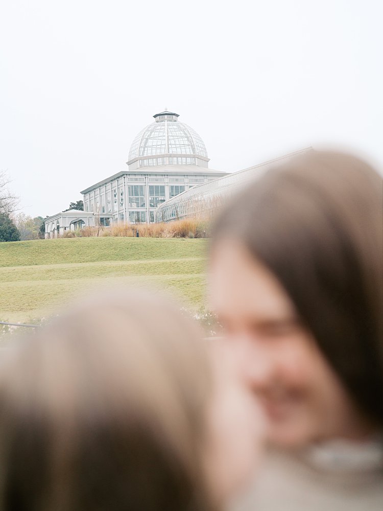 An Image With Two Girls Out Of Focus With The Lewis Ginter Botanical Garden In The Background.