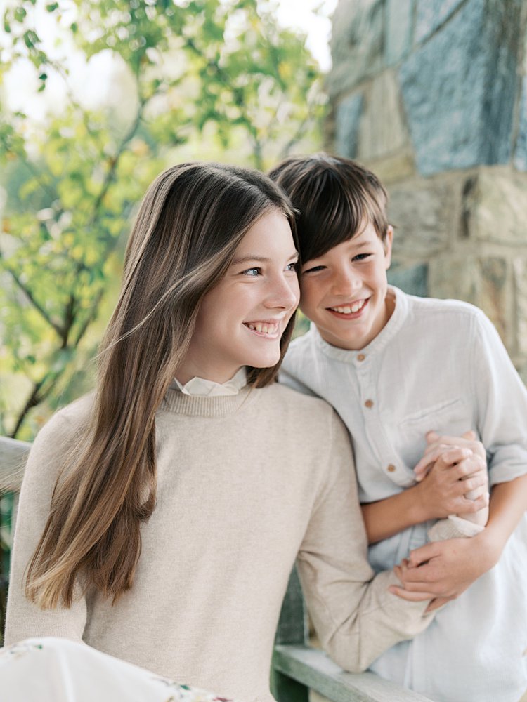 A Teenage Girl Holds Her Younger Brother's Hand As They Both Smile.