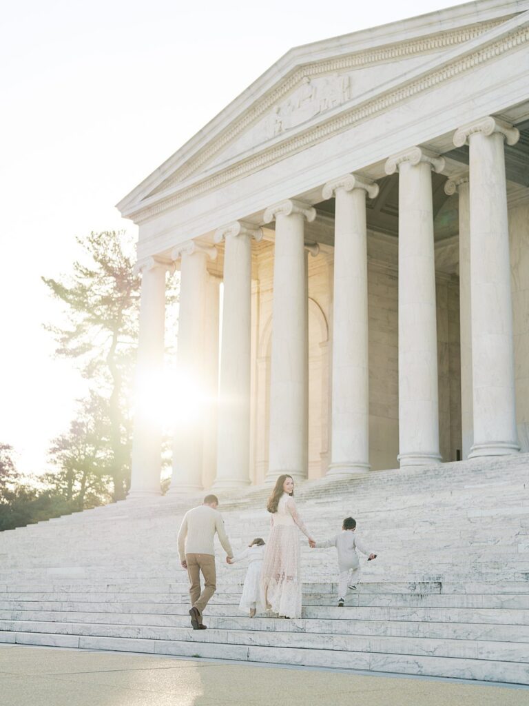 A Soft, Glowing Sunrise Session At The Jefferson Memorial With A Family Walking Up The Steps, Showcasing The Dreamy Light And Iconic Architecture That Make Dc Sessions Feel Timeless.