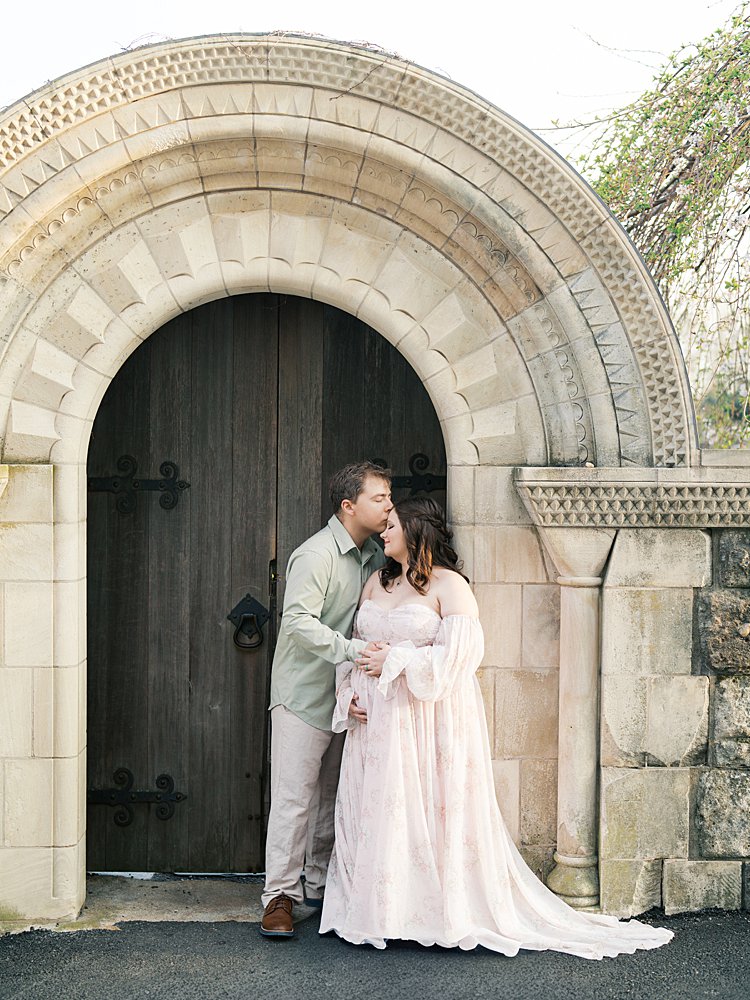Couple Standing In A Stone Archway At The Cathedral During Maternity Photos At The National Cathedral Cherry Blossoms, Highlighting Classic Architecture And Connection.