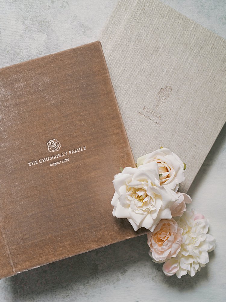 A Linen Heirloom Album And Blush Velvet Keepsake Box With Custom Gold Foil Logos Rest Together On A Marble Surface — The Premium Heirloom Products That Are Part Of What Happens After Your Session With A Fine Art Newborn Photographer.