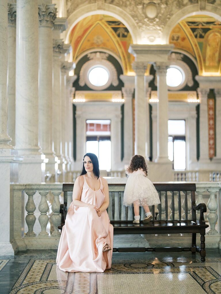 A Mother And Child Sit Together Inside A Grand Historic Building With Ornate Arches And Soft Natural Light, A Refined Indoor Setting That Reflects When Is The Best Time To Get Family Photos In The Dmv, Even Beyond Outdoor Seasons.