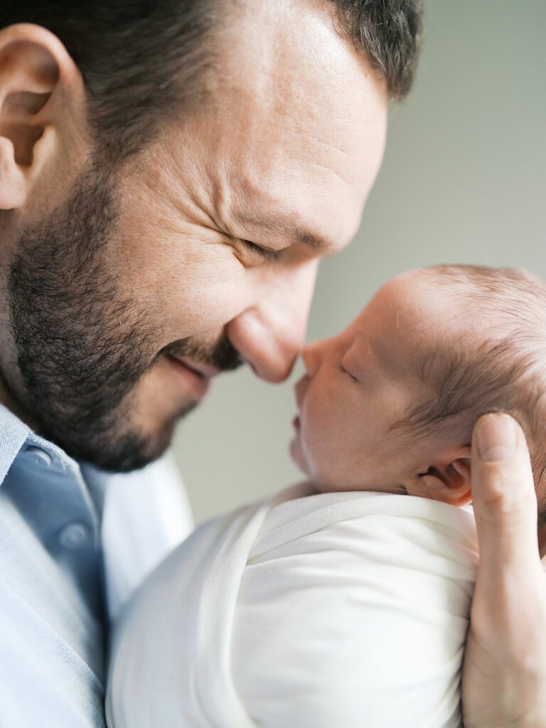 A Dad Touches Noses With His Swaddled Newborn During A Hyattsville, Md Newborn Session, Capturing An Intimate Close-Up Moment Between Father And Baby