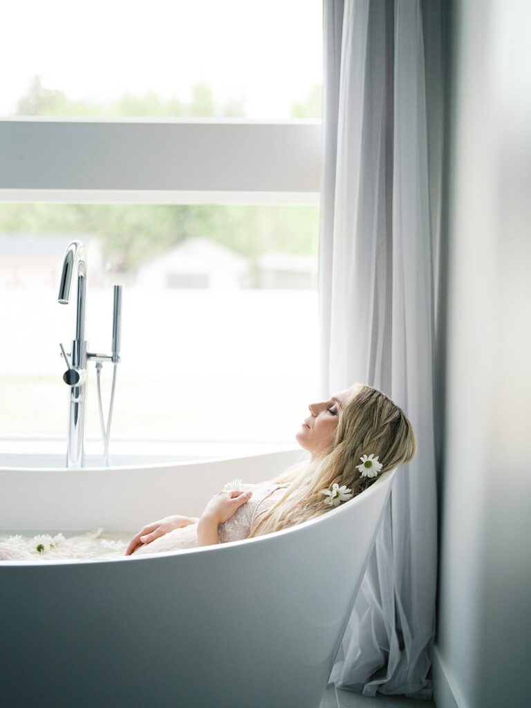 A Blonde Expectant Mother Reclines In A Freestanding Bathtub With Daisy Flowers In Her Hair During A Fine Art Maternity Session In Washington Dc