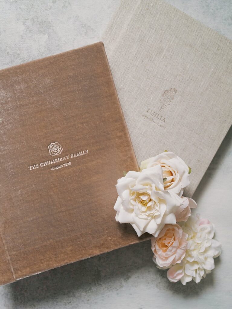 

Luxury Velvet And Linen Heirloom Family Photo Albums Styled With Soft Blush Roses, Showcasing Fine Art Printed Photographs Designed To Be Passed Down For Generations.