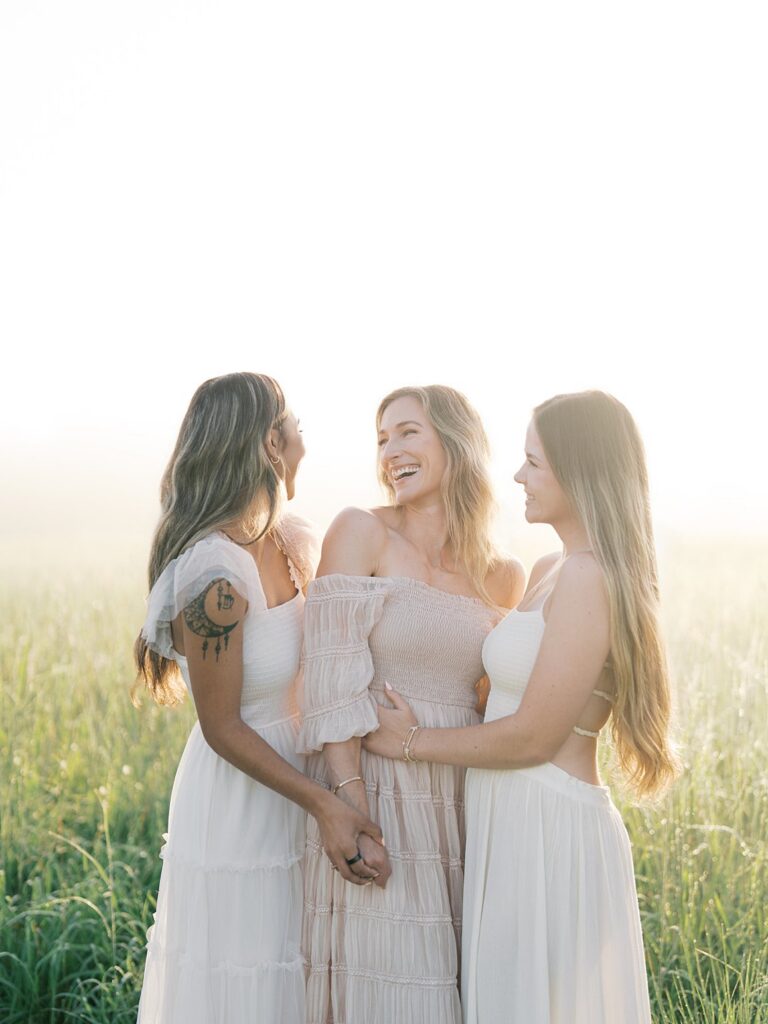 Three Women In Soft Neutral Dresses Laughing Together In A Sunlit Field At Manassas Battlefield, Photographed By A Gainesville Photographer