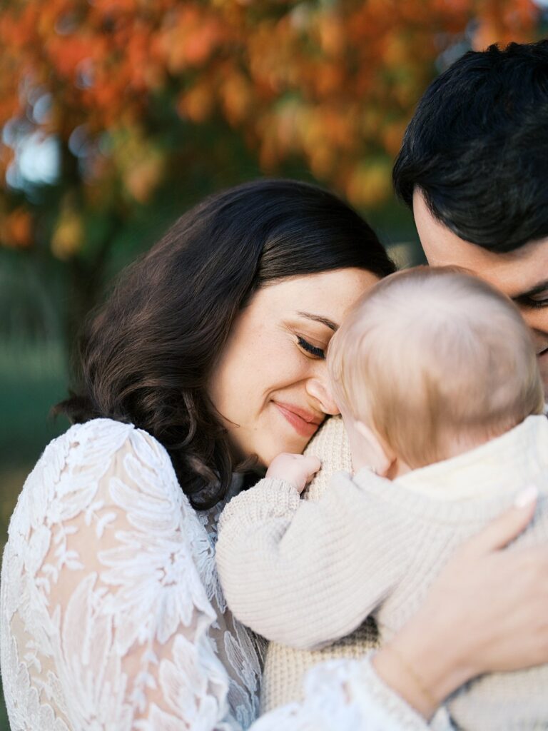 Mother Nuzzles Her Baby Beneath Red And Orange Leaves, A Tender Moment At One Of The Dreamiest Washington Dc Fall Foliage Locations.