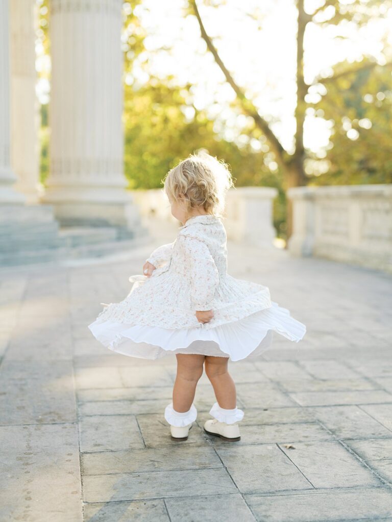 Little Girl In A Lace Dress Twirls Past A Classic Marble Column At Dar Constitution Hall, One Of The Most Elegant Washington Dc Fall Foliage Locations For A Family Session.