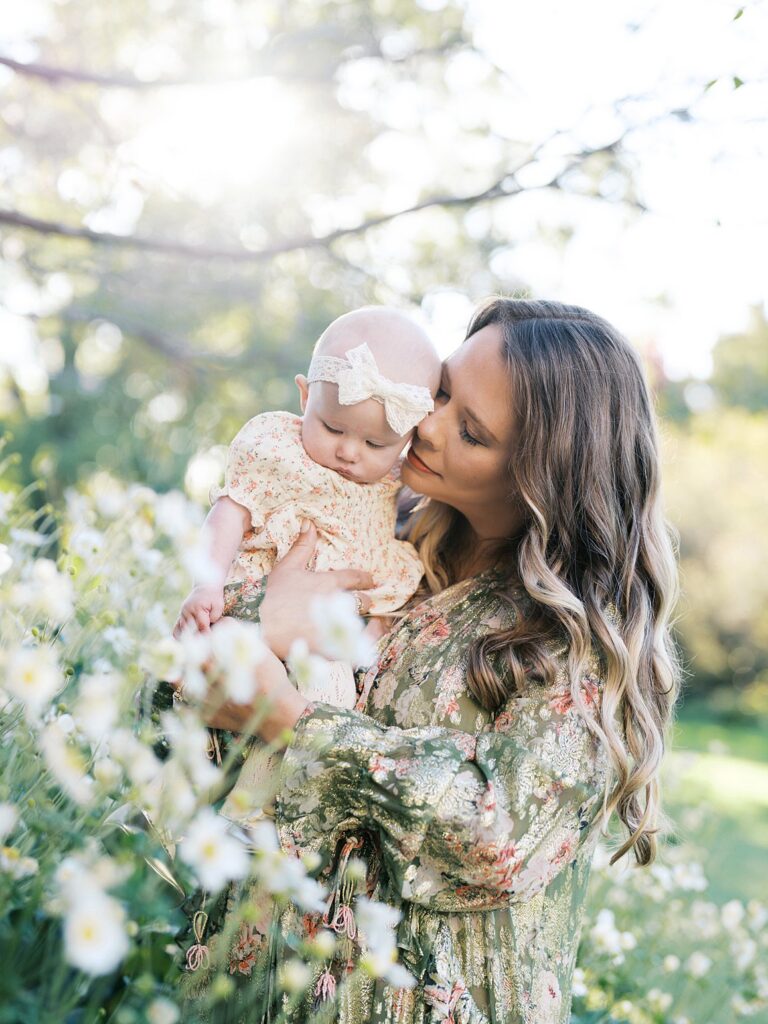 Mother Kisses Her Baby Amid Delicate White Blooms In The Bishop's Garden, A Tender Moment At One Of The Dreamiest Washington Dc Fall Foliage Locations.