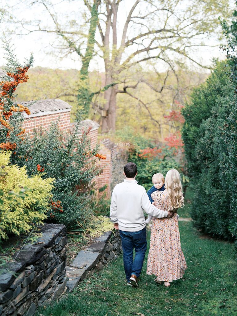 Family Walks A Garden Path Past A Historic Brick Wall And Stone Border At Oatlands, One Of The Best Washington Dc Fall Foliage Locations For A Family Session.