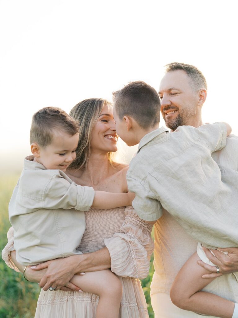 Mother And Father Holding Their Two Young Sons Close In Soft Golden Light, Photographed By A Gainesville Photographer