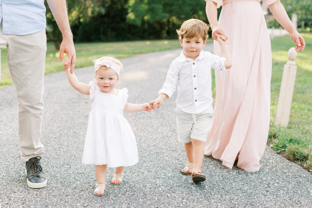 Two young children walking with their parents during their family photos.