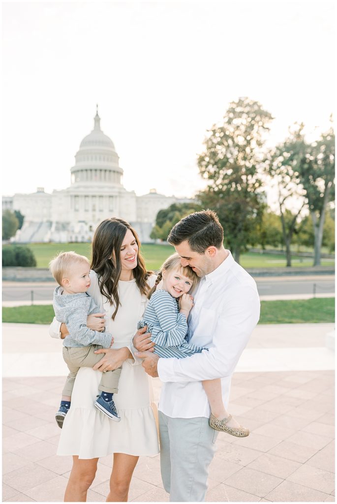 Mother, father, and their two young children standing in front of the US Capitol building during a DC family photo session.