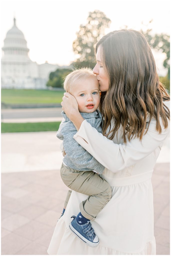 A mother kissing her toddler son in front of the US Capitol Building