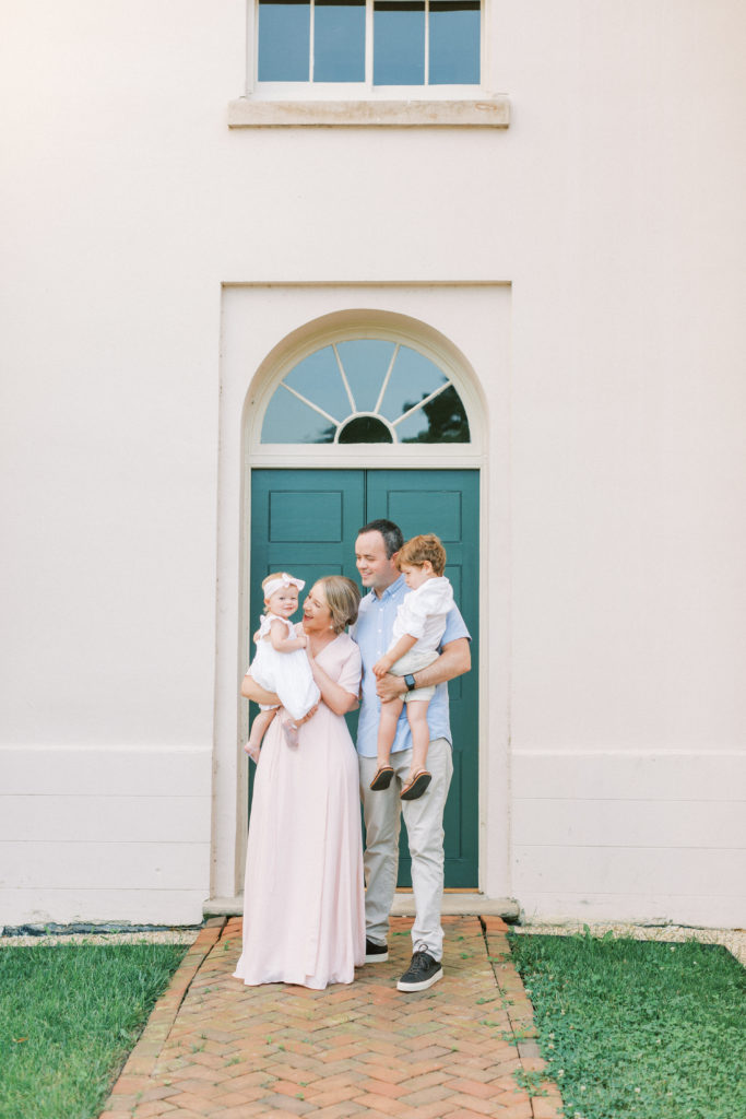 Young family standing in front of green doors during a timeless Maryland family session.