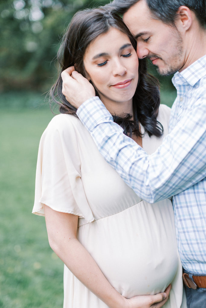 A husband caresses his expecting wife's face during a DC photo session.