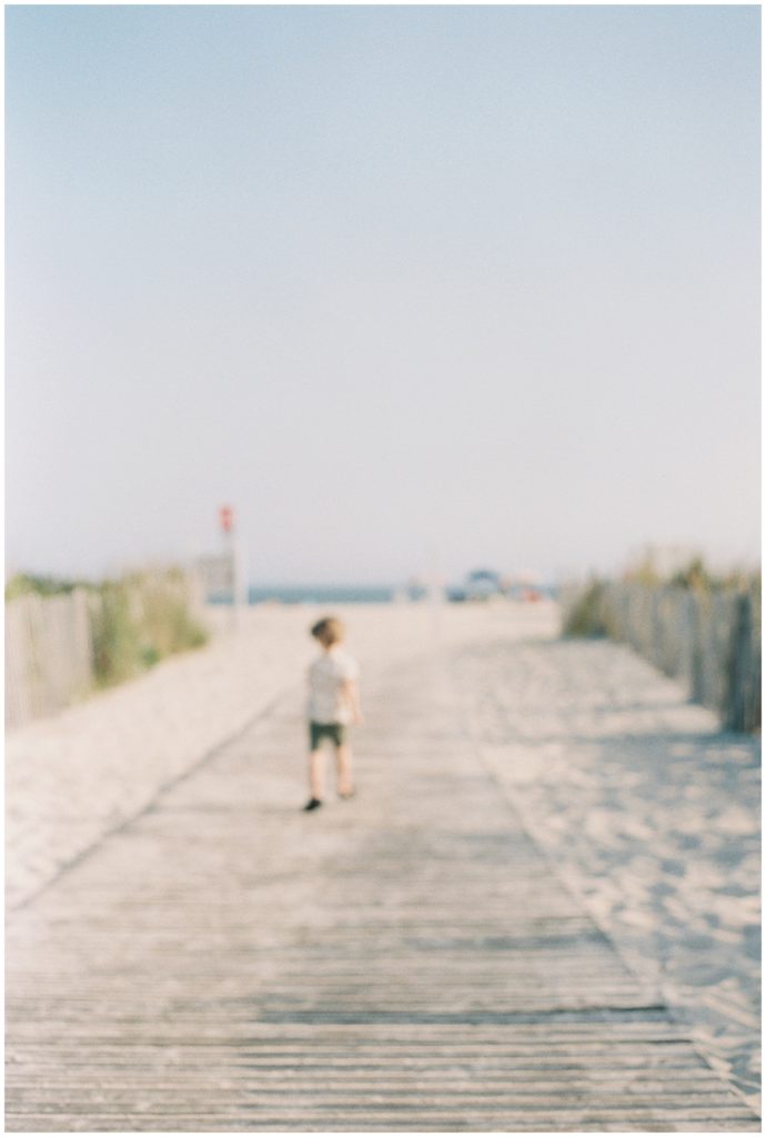 Little boy running along a beach boardwalk - Maryland Film Photographer