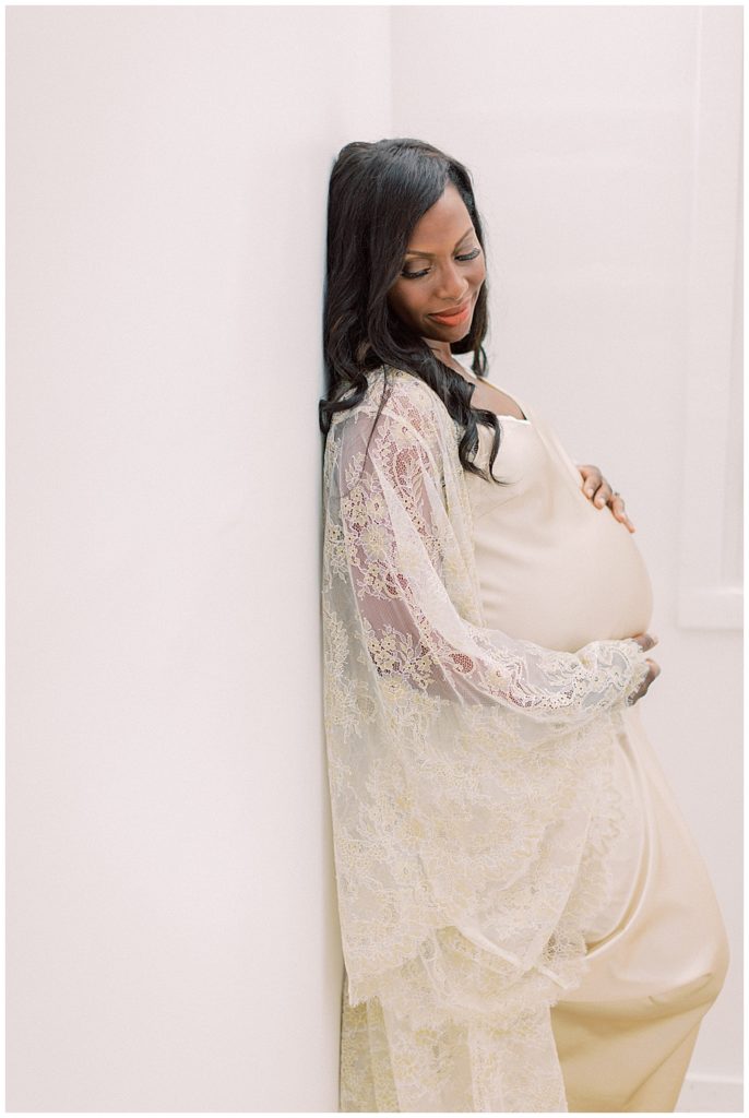 Mother rests against a wall during her DC maternity session in studio