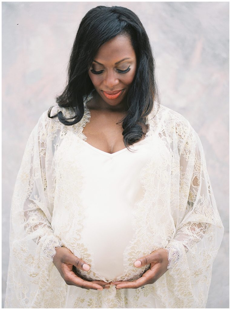 Mother looks down at her belly during studio maternity session in Washington, DC