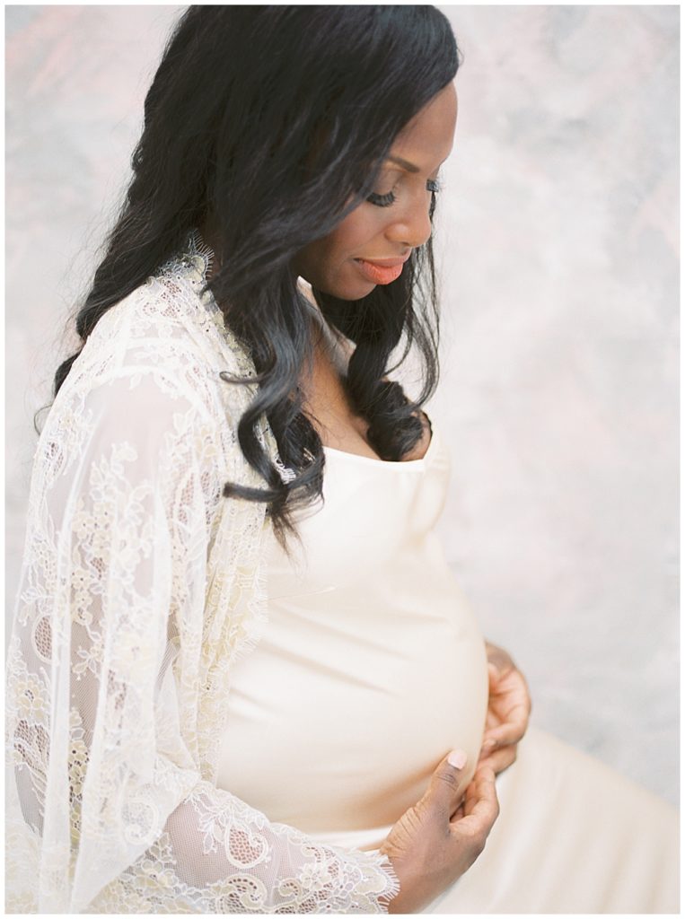 Pregnant mother looks down at her baby bump during Washington, D.C. studio maternity session