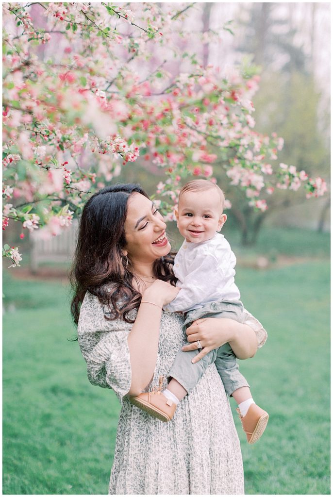 Mother holds her son next to cherry blossom tree in Brookside Gardens in Maryland.