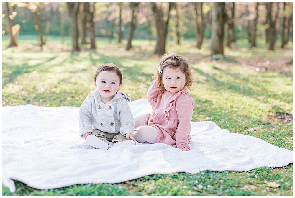 Two young children sit on a blanket by the National Arboretum cherry blossoms