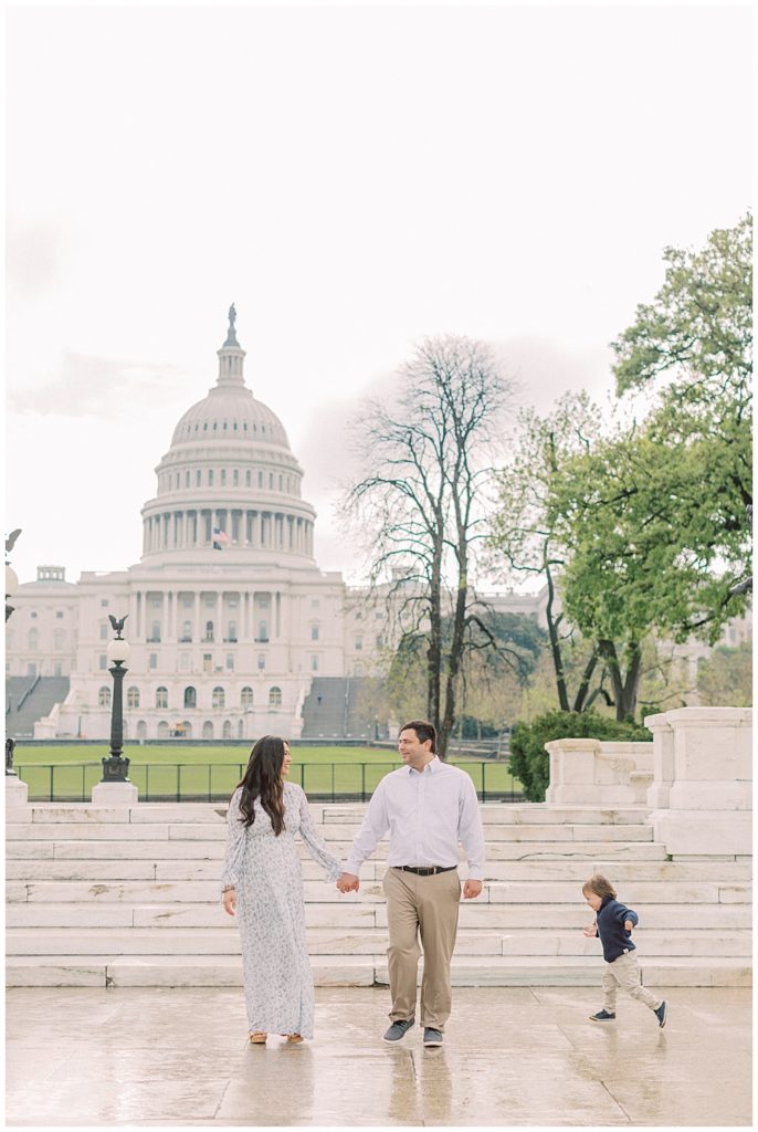 Mother, father, and toddler son walk in front of the U.S. Capitol Building during their family photo session in Washington, D.C.