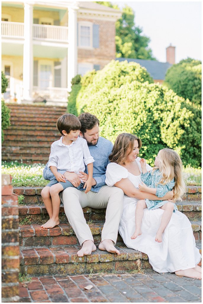 Family sits and smiles on brick steps at Mulberry Fields