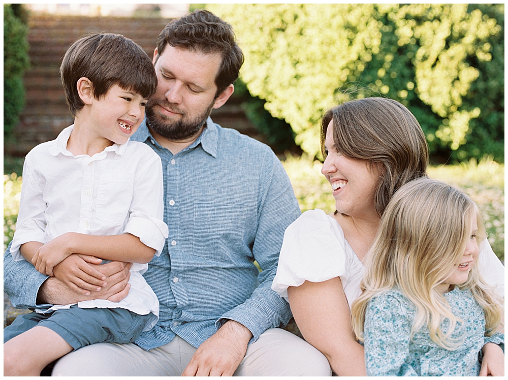 Family smiles at one another during their family photo session in Maryland