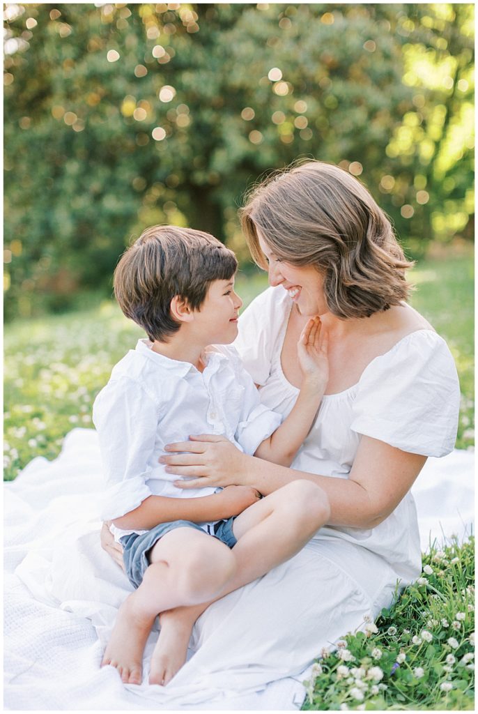 Little boy sits on his mother's lap and strokes her cheek during their Maryland Family Photo session