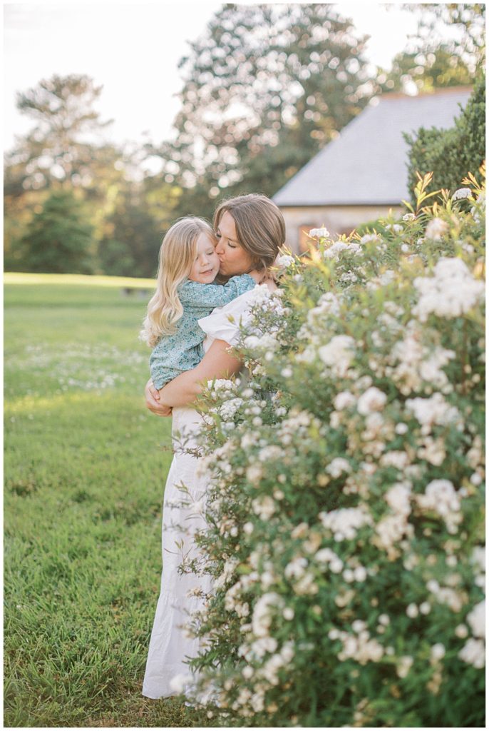 Mother kisses her young daughter's cheek during their family photo session | Family photographers in Maryland