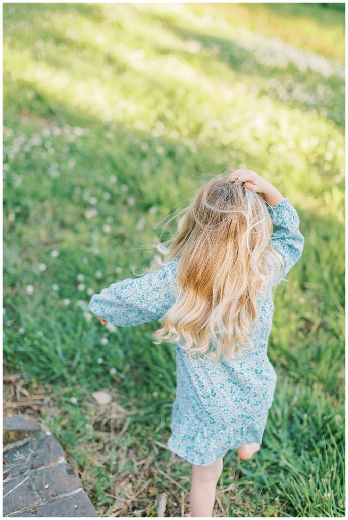 Little girl tugs at her hair while walking away