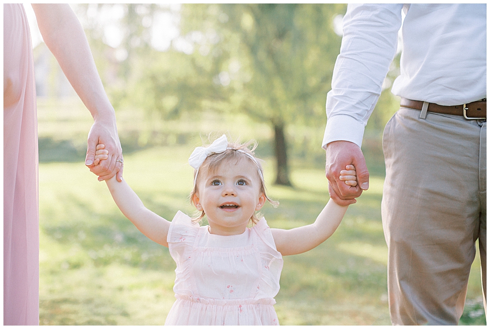 Little girl holds her mother and father's hands 