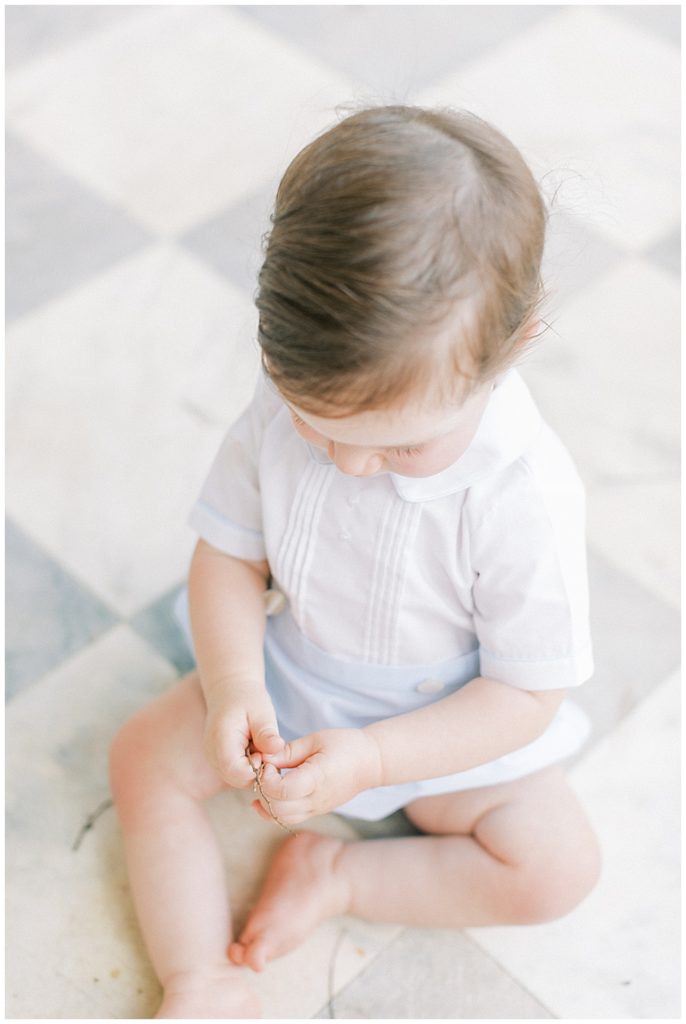 Little boy sits down, playing with a small rock