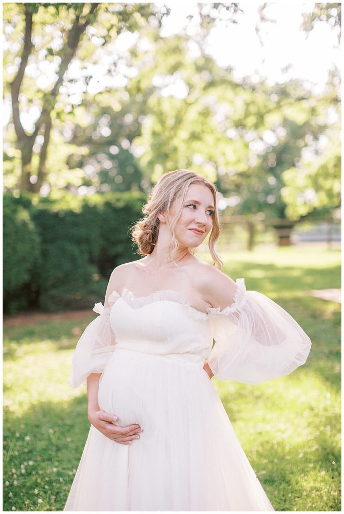 Pregnant woman stands looking over her shoulder during her Salubria maternity session