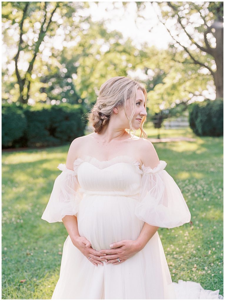 Woman stands with both hands below her pregnant belly during her Northern Virginia maternity session