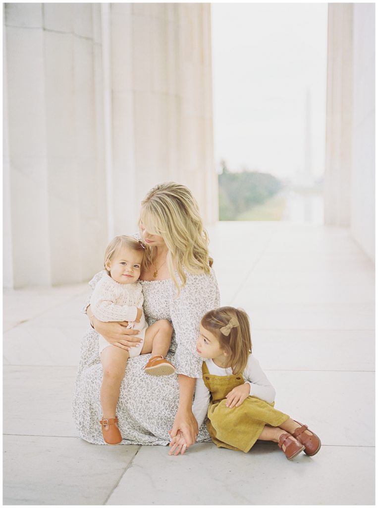 Mother sits with her two daughters at the Lincoln Memorial during her DC photo session