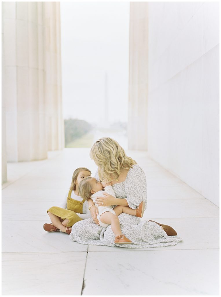 Mother sits and nurses her young daughter at the Lincoln Memorial in DC