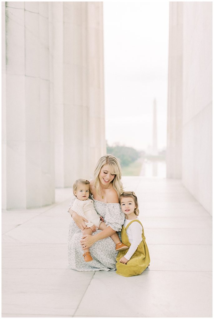 Mother looks at her two daughters while sitting down at the Lincoln Memorial
